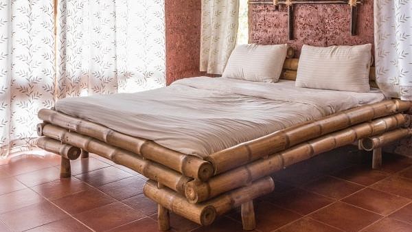 bedroom with a wooden bed frame, tan walls, and a window with patterned curtains.