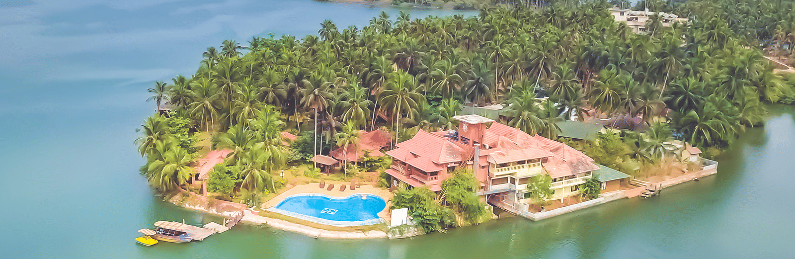 Aerial view of Paradise Lagoon Resort, Udupi, featuring a pool and water all around.