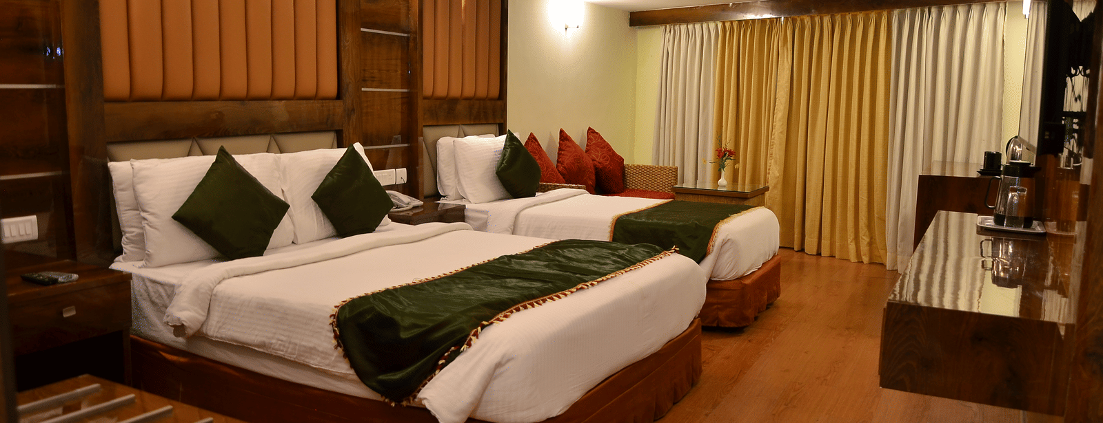 A family room with twin beds, stylish decor, and green accent cushions for a comfortable experience - Benzz Park, Kodaikanal