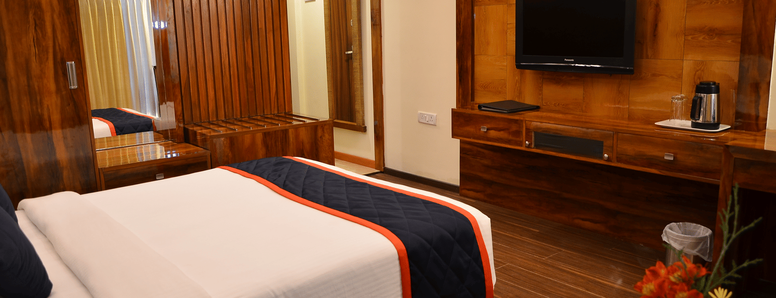 A cosy room with a queen bed, wooden panelling, and wall-mounted TV for a relaxed stay - Benzz Park, Kodaikanal