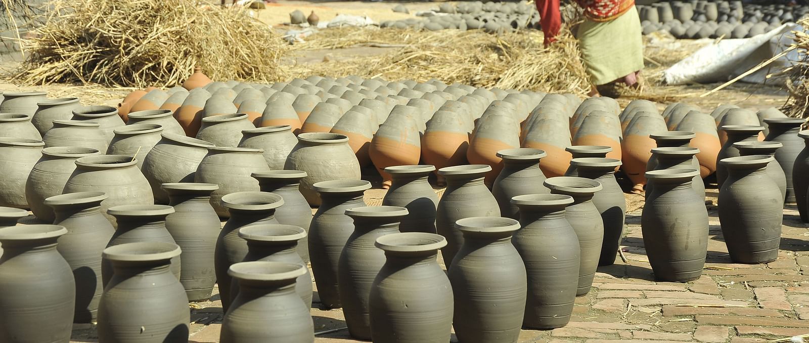 A pottery lined up on a ground which are kept for drying under the sun