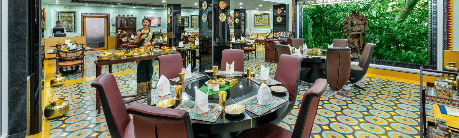 Well-lit private dining room with a long table set for a meal, featuring bright yellow and green decor and a large window overlooking greenery.