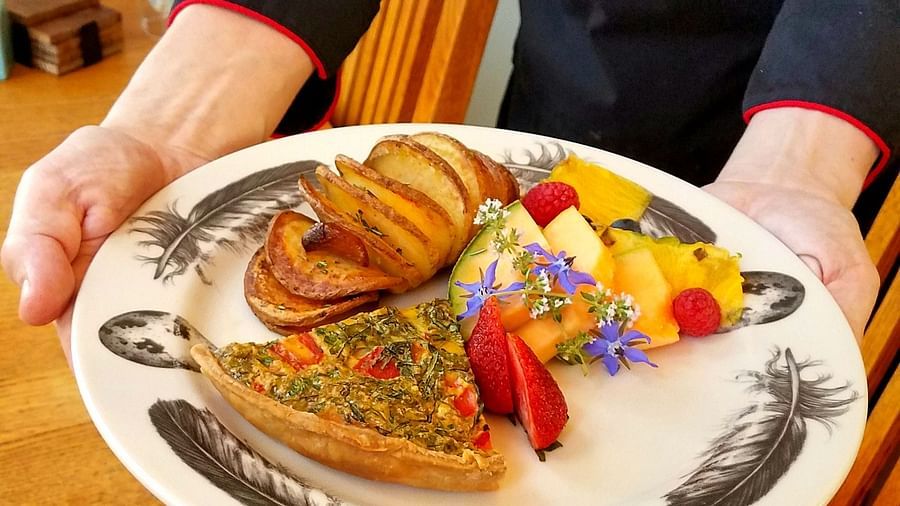 A staff member presenting a beautifully plated meal - Brewery Gulch Inn & Spa