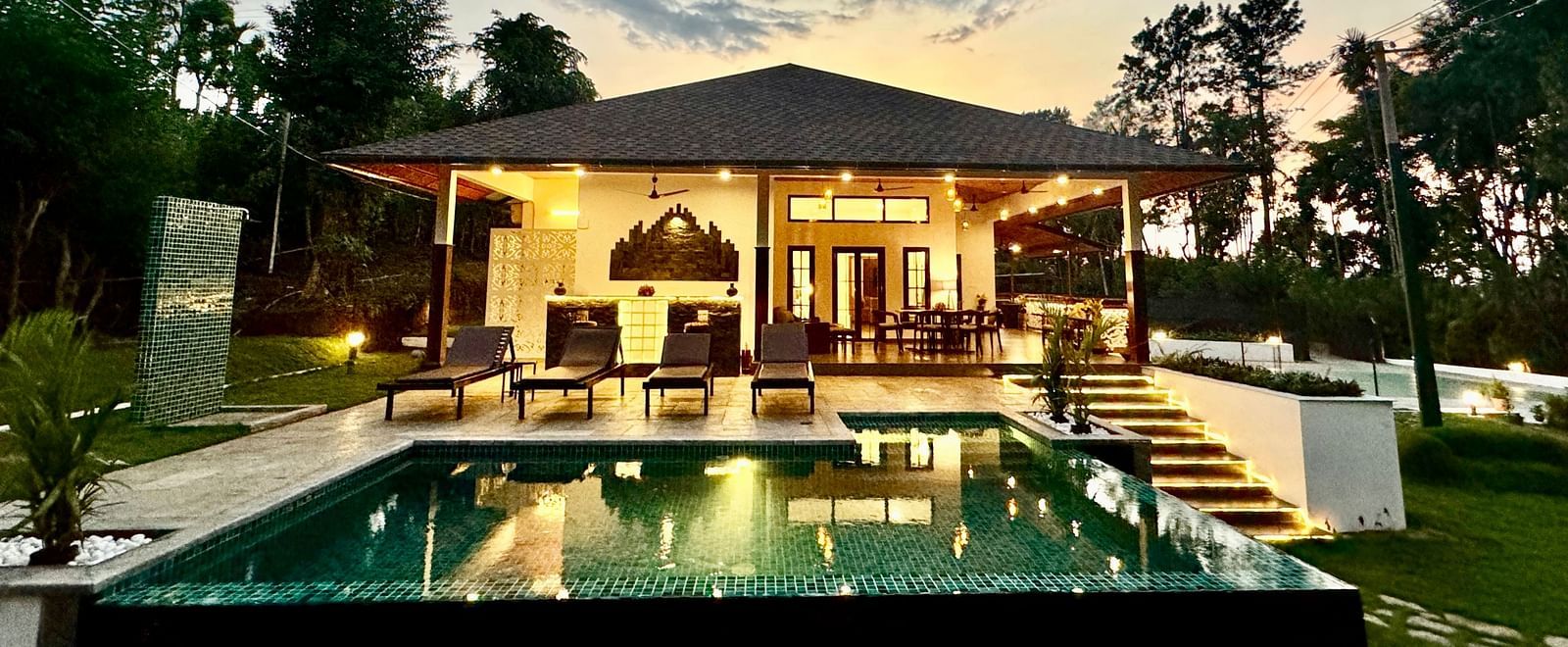 Elegant villa with a private pool reflecting the twilight sky and surrounding trees - BluSalzz Collection - Tranquil Resort, Wayanad