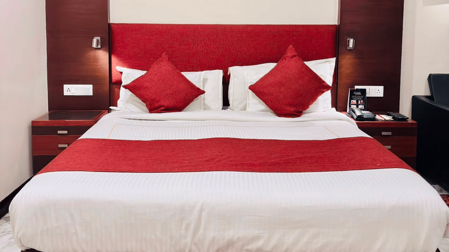Front view of the double bed with a red bed runner along with 2 bed side tables - Amantra Comfort Hotel