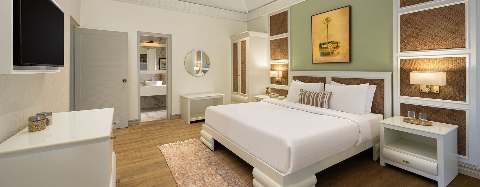 An image of a bedroom with double size bed, bedside table on either side, photos hanged on the wall and four windows from which natural lights are coming in - The Riverview Retreat,  Corbett