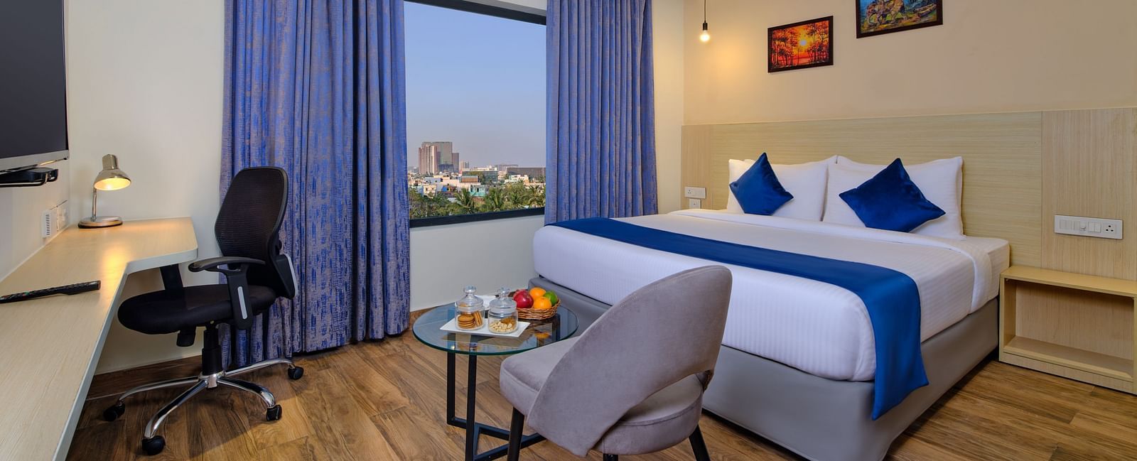 A room at Essentia Premier Hotel, Chennai with a double bed, a television and a work desk and chair