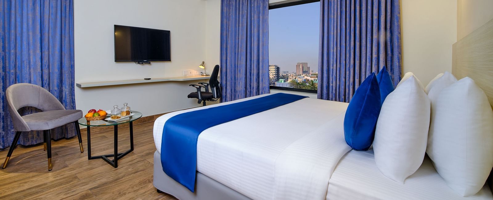A room at Essentia Premier Hotel, Chennai with a double bed, a television and a work desk and chair