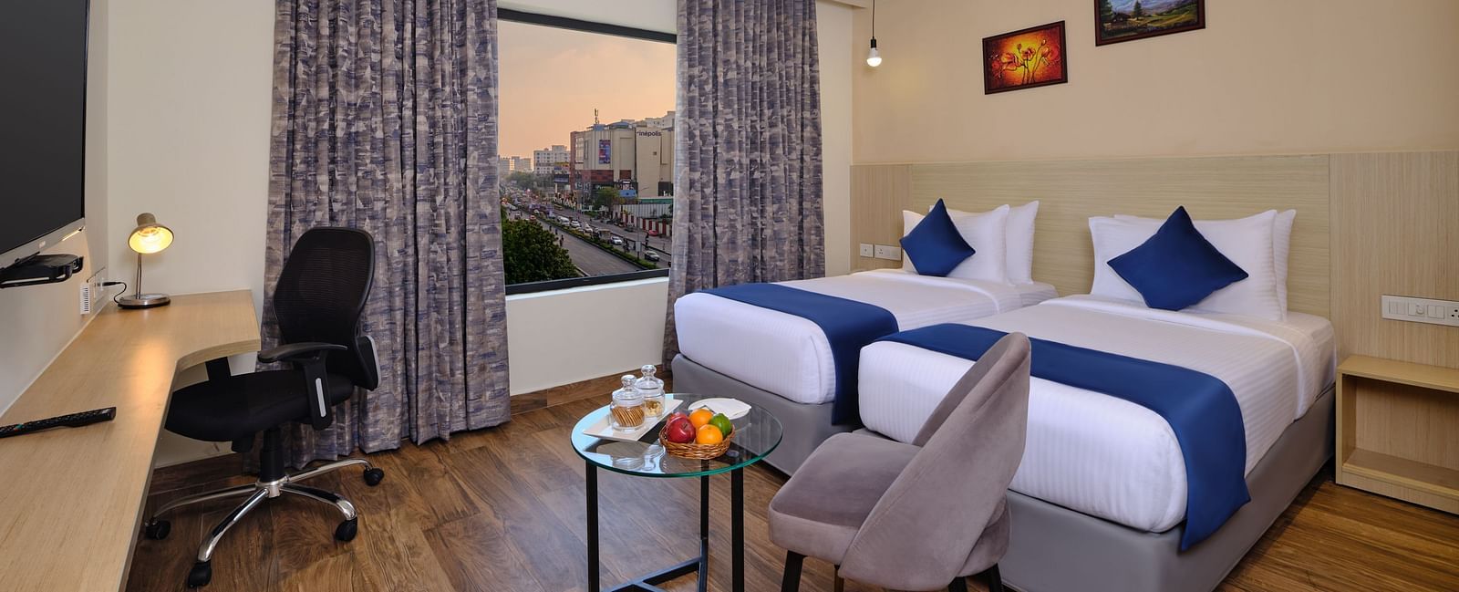 A room at Essentia Premier Hotel, Chennai with twin beds, a television and work desk and chair