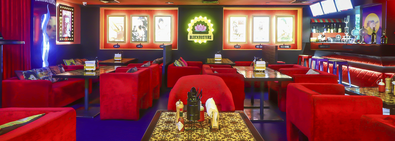 A dining area with red sofas, wall-mounted posters and bright ceiling lights at Infiniti Hotel, Indore.