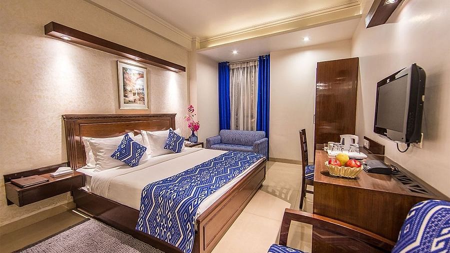 Hotel room at Rockland Hotel, CR Park, with vibrant blue accents, king-size bed, work desk, and modern wooden furnishings.