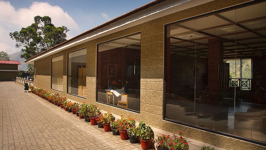 Abad Copper Castle exterior with a covered walkway, large glass windows, and potted plants line the walkway.