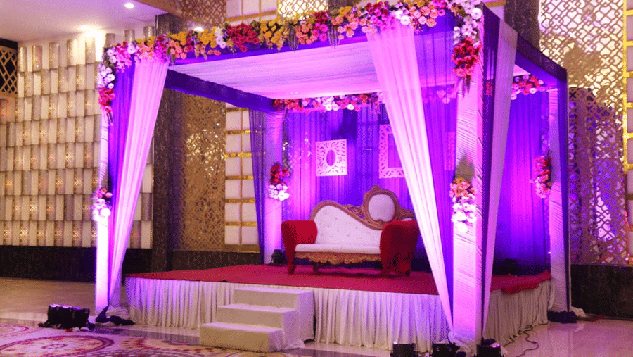 An outdoor space with a chair placed on a stage that is decorated with curtains and lights for an event. | The Bristol Hotel