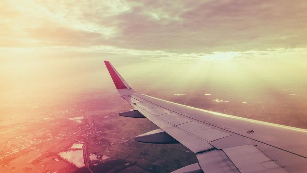 Aeroplane flying in the sky with the sun's rays showing from the clouds