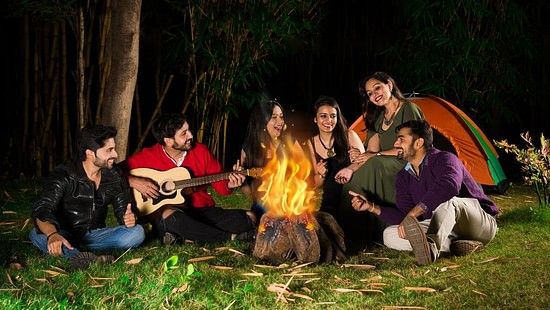 Group of Friends sitting in a circle around a fire camp