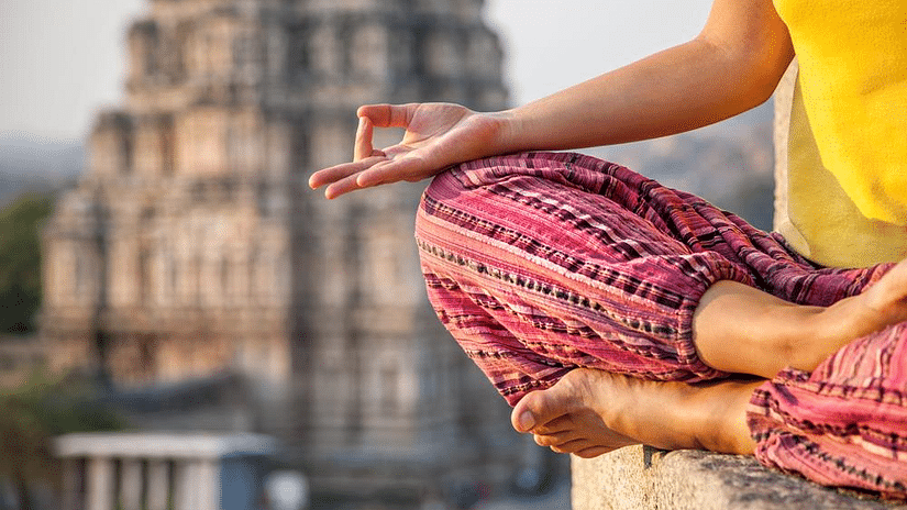 A woman practising a yoga pose in front of a temple