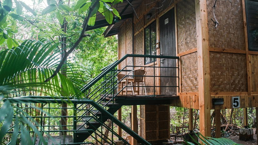A wooden tree house with a staircase in the front, in the middle of a forest at Nature Trails Sajan 