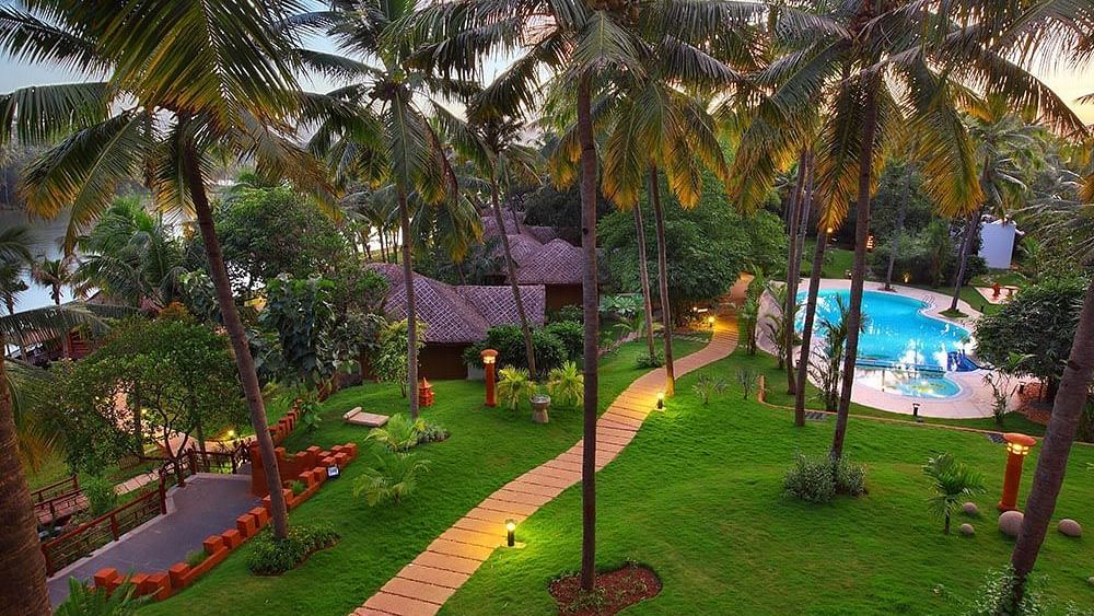 Facade view of Fragrant Nature Kollam, featuring a pool and surrounding trees