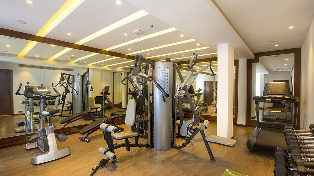 Gym with all the equipment neatly arranged, ample space around, and mirror walls with lighting