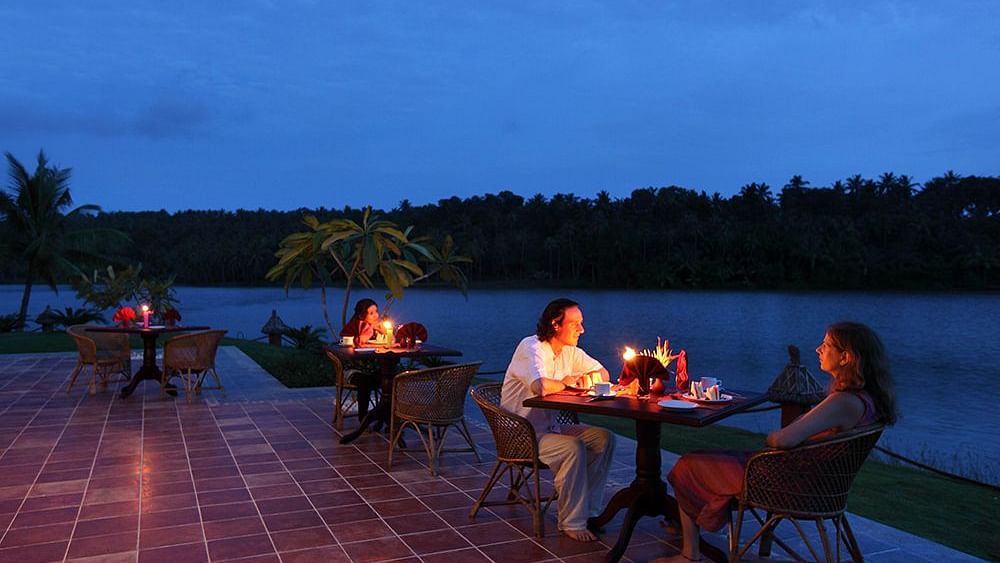 A couple enjoying a candlelit lakeside dining setup with a breathtaking view.