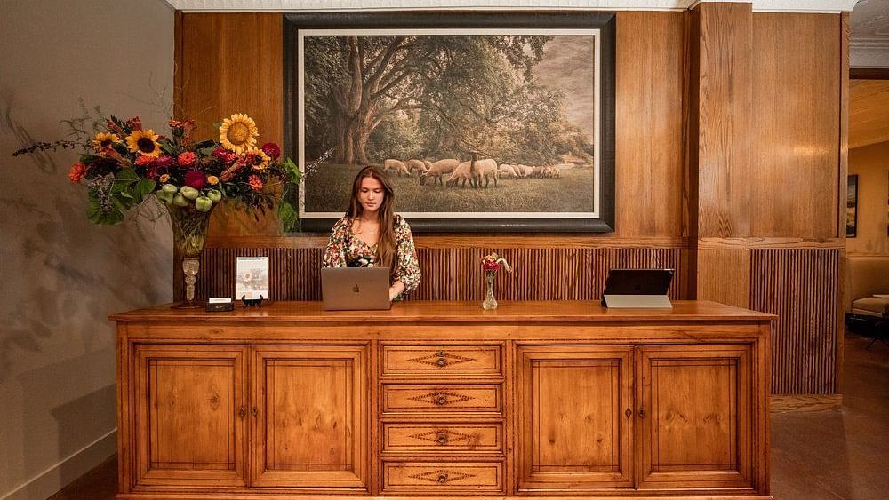 A reception area with a wooden counter, a large painting on the wall, and a warm, inviting atmosphere for guests - The Grand Hotel & Ballroom, McKinney