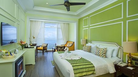 Spacious bed with furniture for seating, a bedside table, and a wall-mounted television