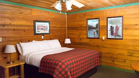 A wood-paneled room with a double bed at Shaver Lake Village Hotel.