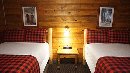 A room with twin beds and a side table placed in between them at Shaver Lake Village Hotel.