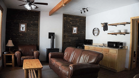 A room at Shaver Lake Village Hotel with a double sofa placed in its center and a wooden coffee table placed in front of it.