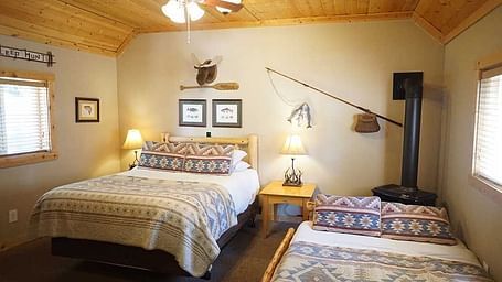 A room with a double bed, side tables, and wooden paneling on the ceiling at Shaver Lake Village Hotel.