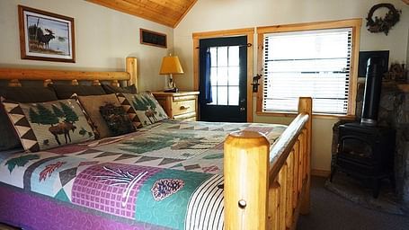 A room with a double bed and wooden paneling on the ceiling at Shaver Lake Village Hotel.