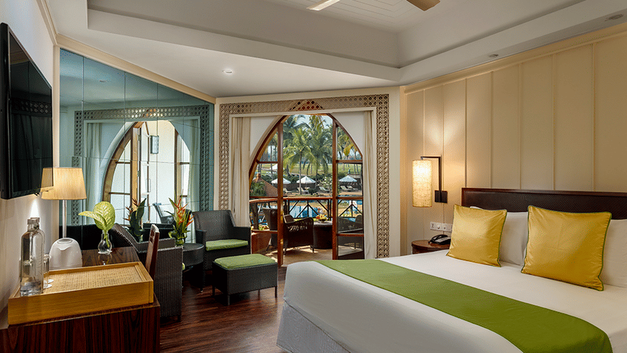 a double bed, tv, chairs and lamps inside Deluxe Room - Caravela Beach Resort Goa