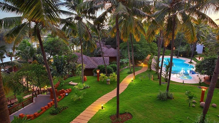 Facade view of Fragrant Nature Kollam, featuring a pool and surrounding trees