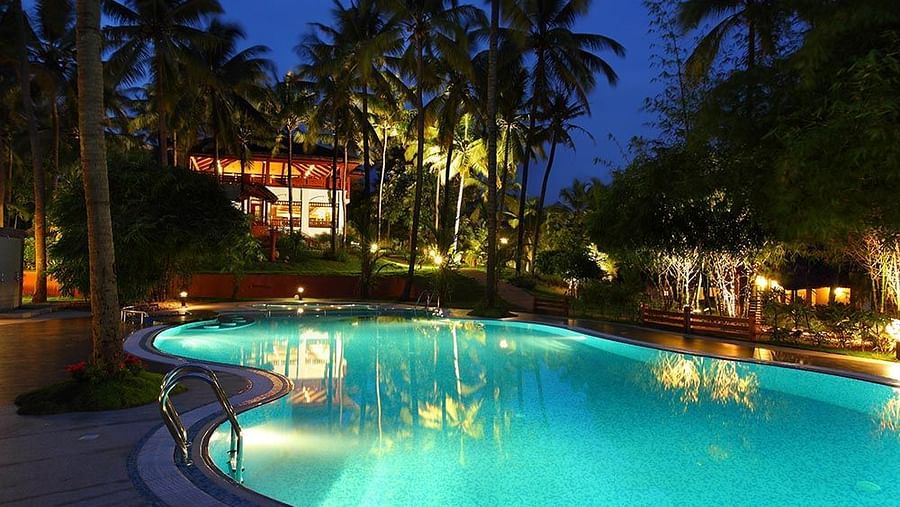 Pool area at night with surrounding lighting and trees nearby