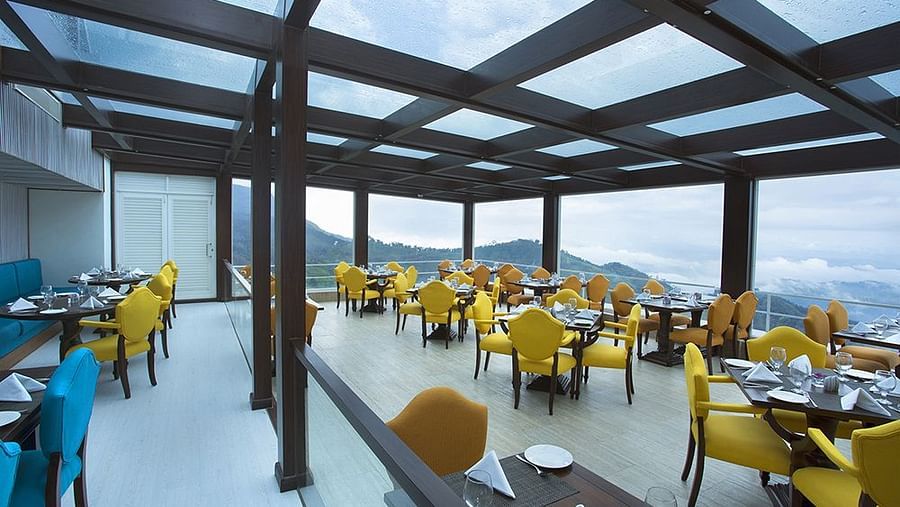 Multi-cuisine restaurant with a warm ambience and tables set ready at Fragrant Nature Munnar