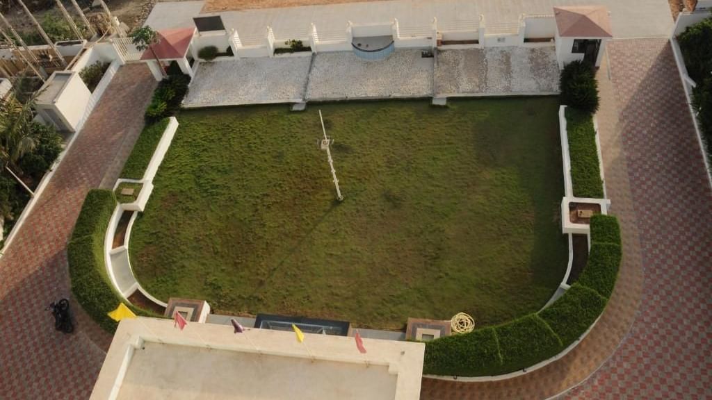 A hotel with a well-maintained green lawn and outdoor seating at dusk | Daksh The Madhuvan Suites