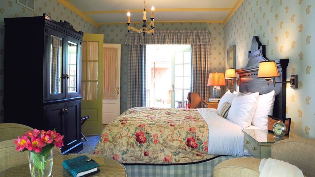 A vibrant and spacious guest room at the Tallman Hotel, featuring a large bed and direct patio access.