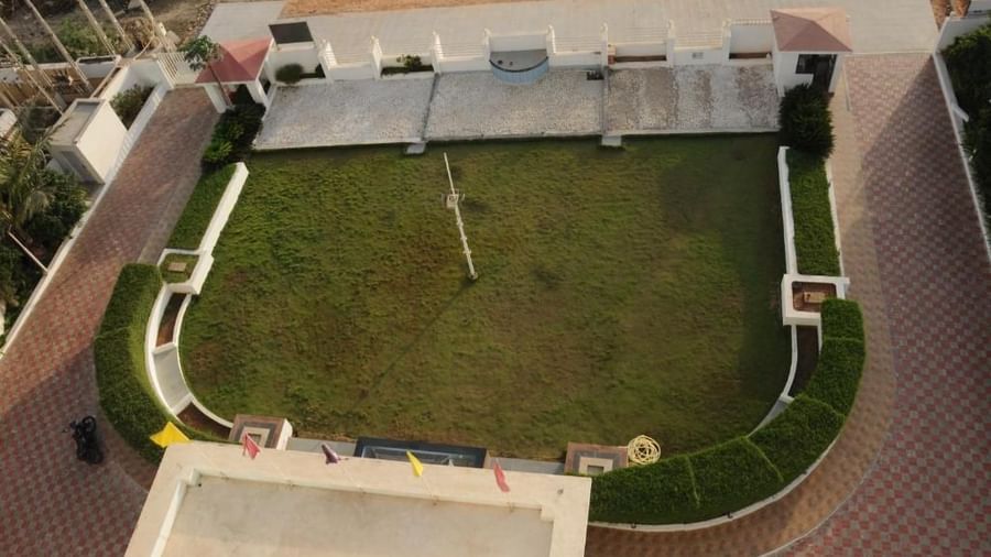 A hotel with a well-maintained green lawn and outdoor seating at dusk | Daksh The Madhuvan Suites