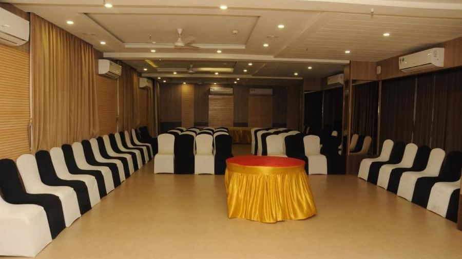 A banquet hall set up with tables and chairs, featuring dark and white covers. | Banquet Hall | Daksh The Madhuvan Suites