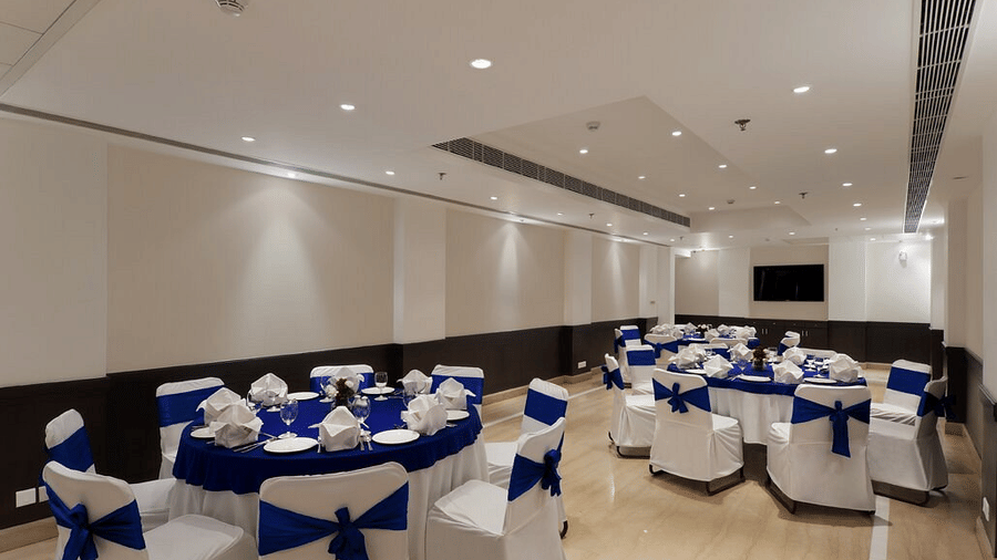 Round tables are elegantly set with blue linens and white chair bows at Eastlynn Collections Huda City Centre, Gurugram.
