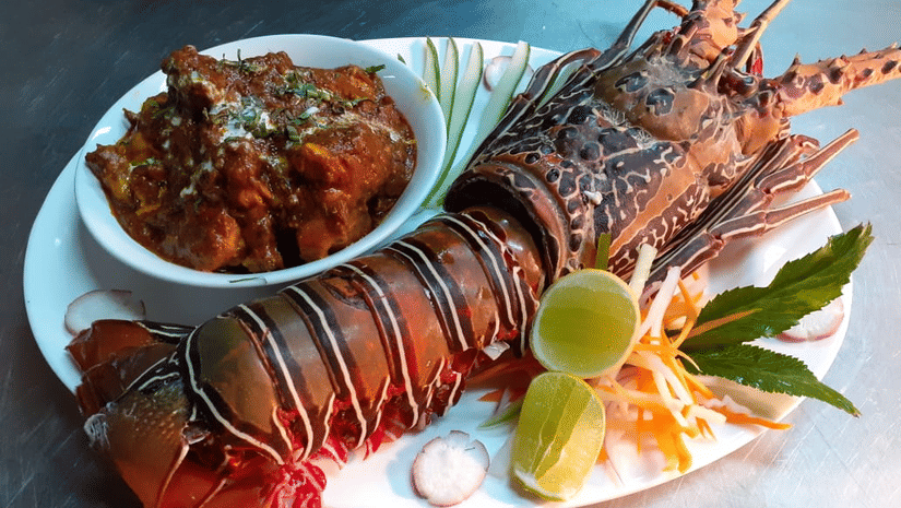 A cooked lobster on a plate with garnishes