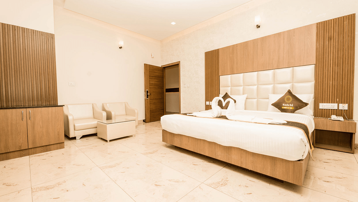 Super Deluxe Room With Balcony featuring a king size bed, a seating area, and minimalist decor.- Sukhi - A Luxury Stay Inn, Chikkamagaluru 