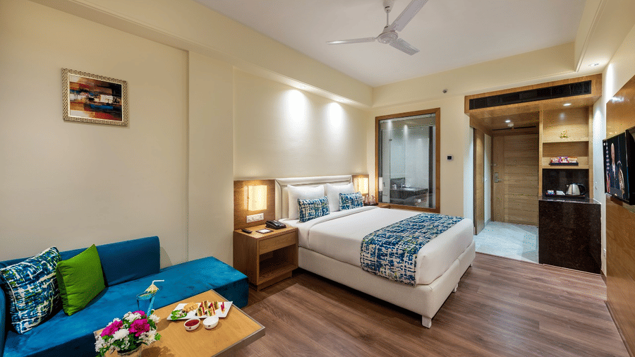 Cozy club room with a modern twin-bed setup, warm lighting, a comfy couch, and playful table decor.