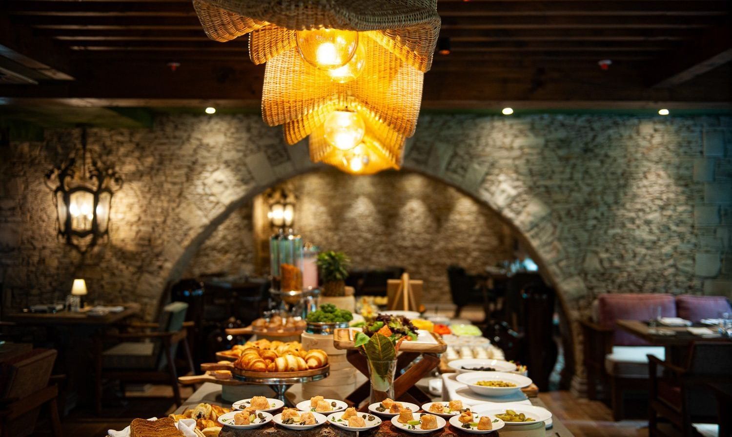 Close-up shot of the buffet table spread with well-plated dishes placed under the warm lighting from the unique chandelier at the Mila restaurant at The Evren, Vagator.
