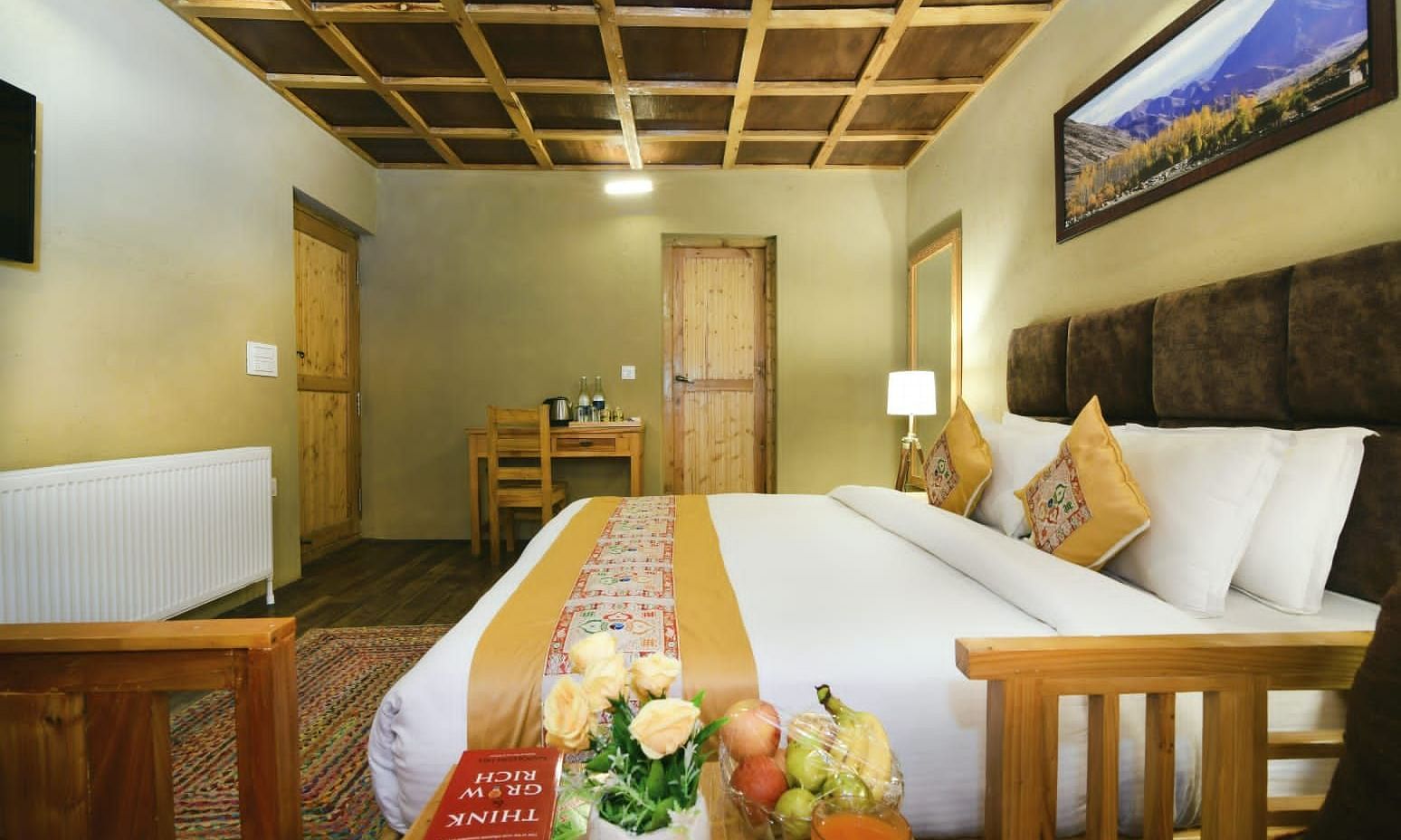 Standard Cottage featuring a king size bed with white linens and a yellow runner, flanked by wooden bedside tables at White Sands Resort, Ladakh.