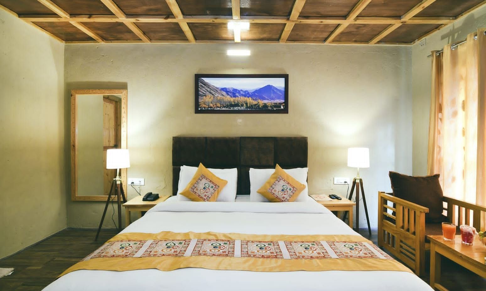 Standard Cottage with a king size bed, bedside tables, lamps, and a painting on the wall at White Sands Resort, Ladakh.