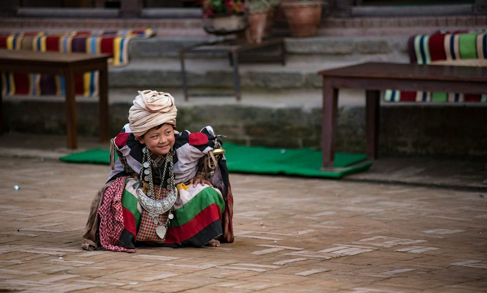 Young boy wearing tradition attire sitting on the ground