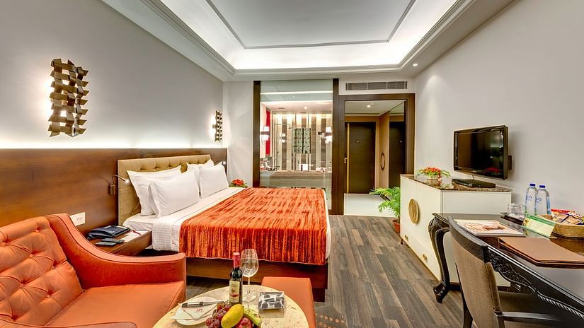 A modern hotel room with a plush king size bed, a comfortable seating area and warm toned decor, perfect for a relaxing stay – Hotel Hindusthan International, Kolkata