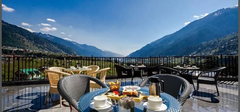 Image of the outdoor seating area at the resort overlooking the hills on a bright day | DLS La Serene Manali