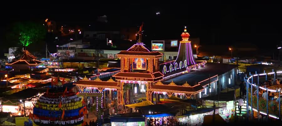 A beautifully illuminated temple complex at night, with surrounding structures lit up.